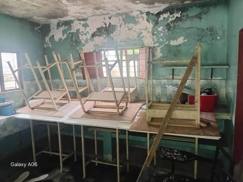 Salón de la telesecundaria Buenavista con paredes despintadas y sillas apiladas sobre mesas