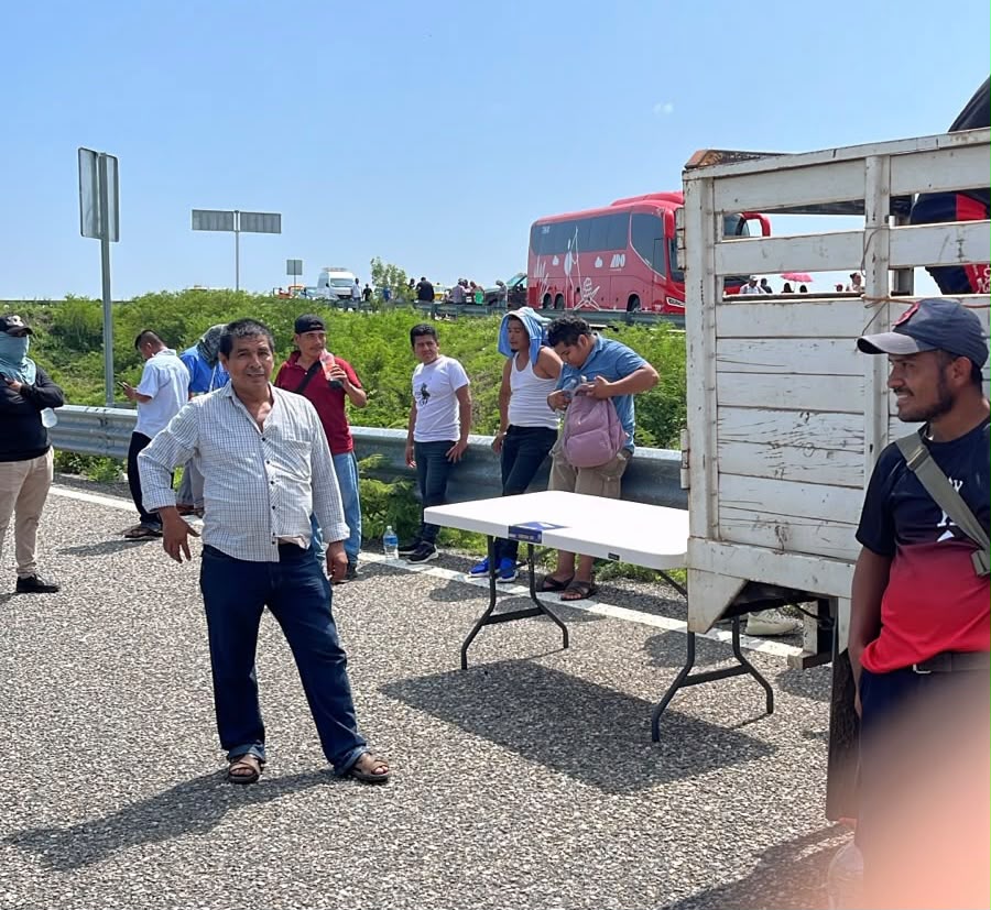 Manifestantes sobre la carretera con un autobús de pasajeros detenido al fondo