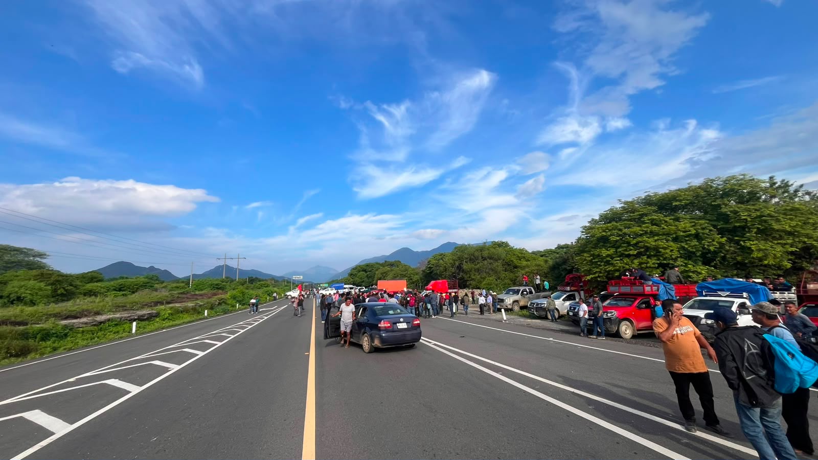 Vista amplia de la carretera federal 190 bloqueada, con vehículos y personas sobre el asfalto