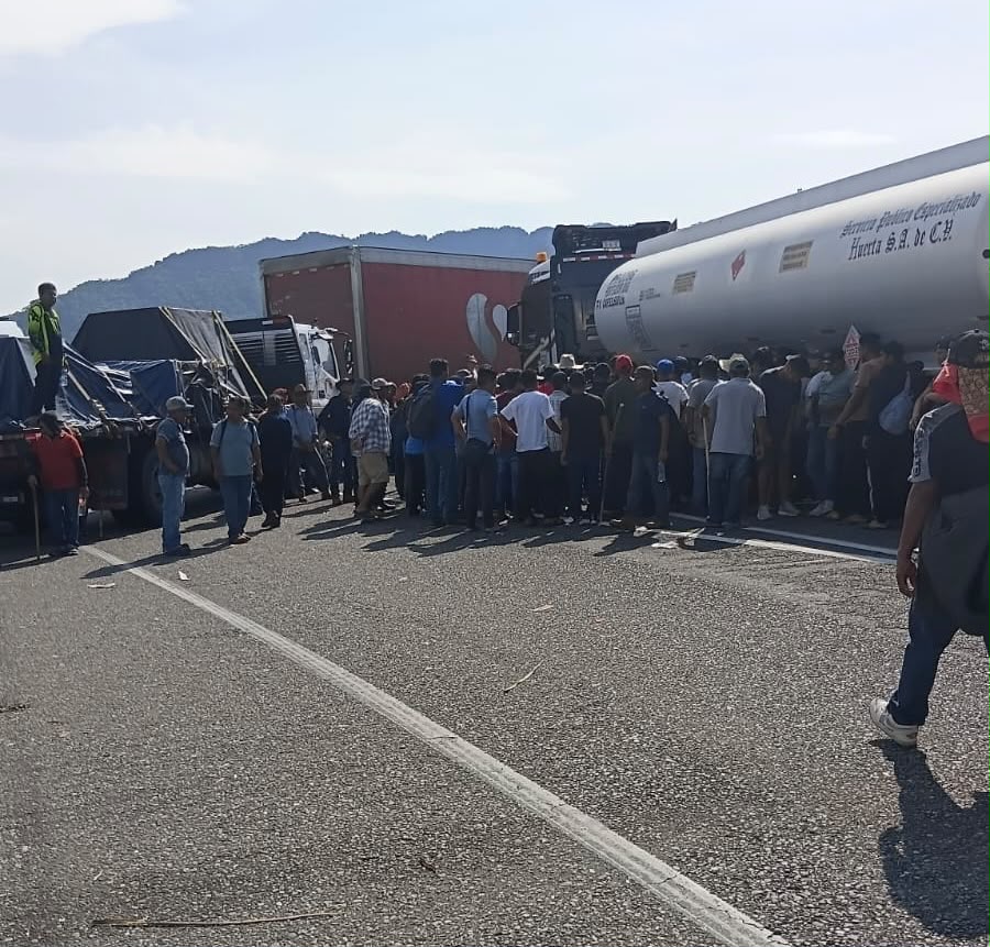 Manifestantes frente a tráileres y una pipa detenidos sobre la carretera federal 190