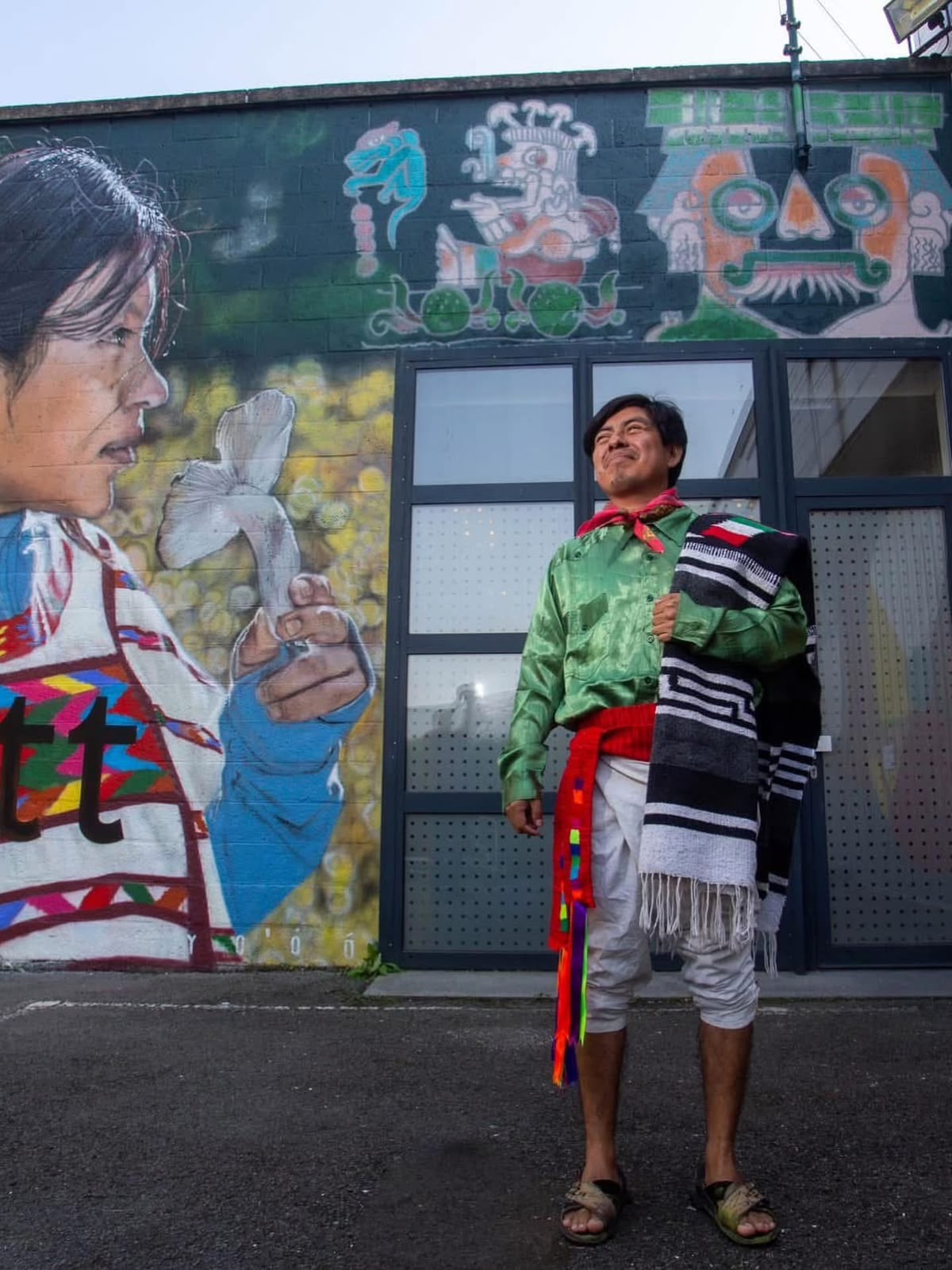 El artista Joel Merino junto a un mural