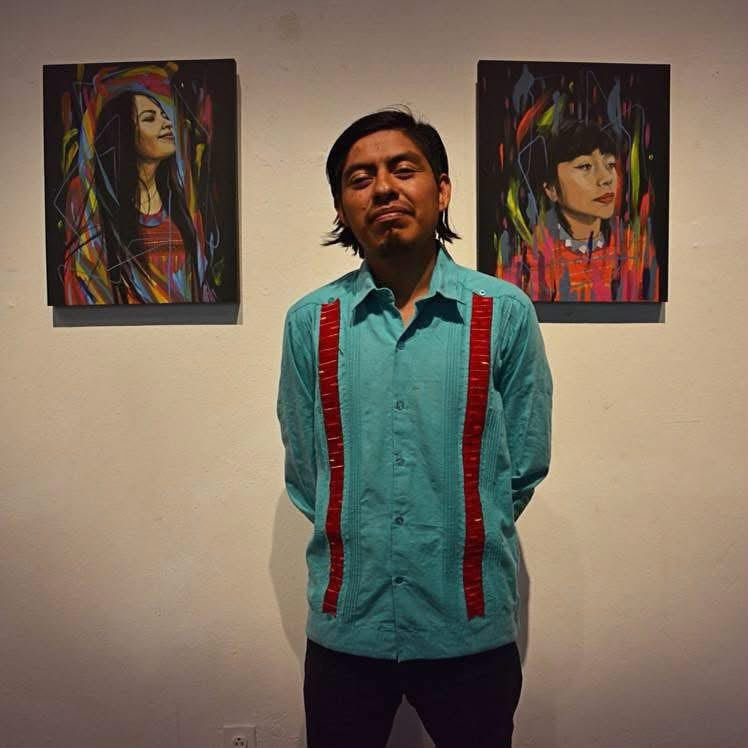 El artista Joel Merino frente a dos pinturas